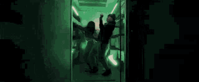 a man is standing in a dark room with a green light .