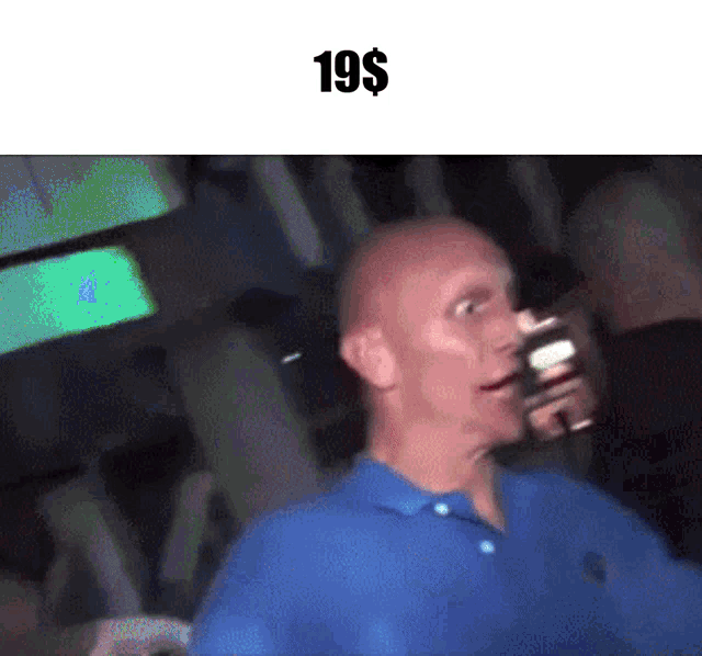 a bald man in a blue shirt is standing in a dark room with the price of 19 dollars on the bottom