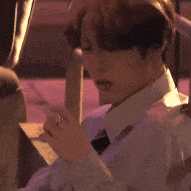 a close up of a person smoking a cigarette while wearing a white shirt and tie .