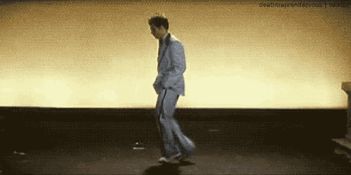 a man in a suit is dancing on a stage in a room .
