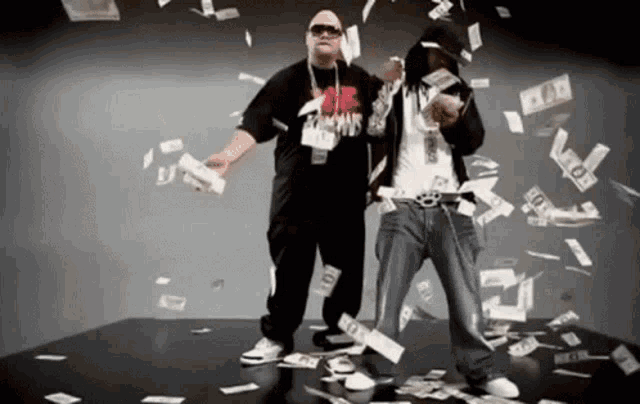 two men are standing in front of a pile of money and one of them is wearing a shirt that says ' famous ' on it