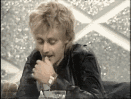 a man in a black jacket is sitting at a table eating a piece of food .