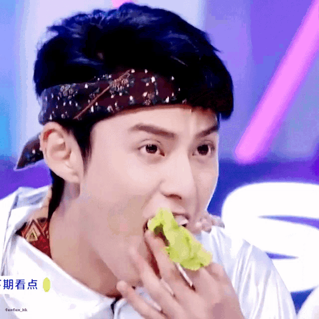 a close up of a person eating a piece of lettuce