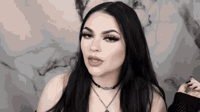 a woman with long black hair is wearing a choker necklace and a black shirt .