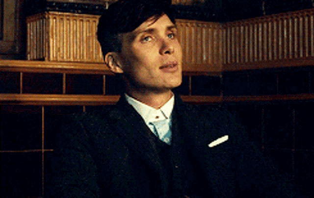 a man wearing a suit and tie is smiling with his eyes closed