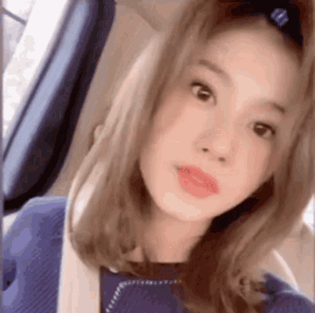 a woman is taking a selfie in a car while wearing a blue sweater .