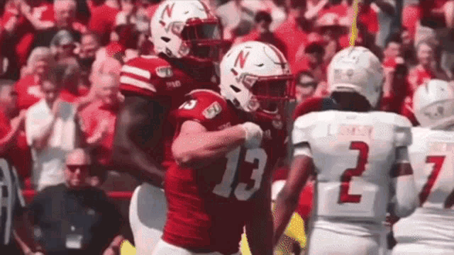 two football players are hugging each other on the field .
