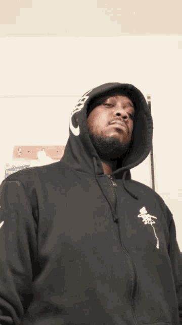 a man wearing a black hoodie with a white logo on the front