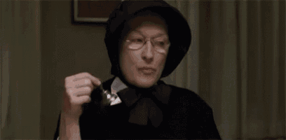 a woman wearing glasses and a black hat is holding a spoon .