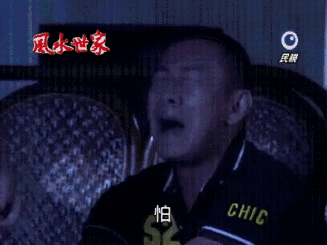 a man is crying in front of a tv screen that says ' 民 視 ' on it