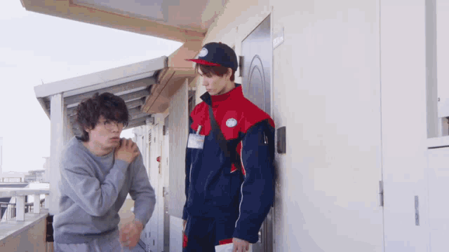 a man standing next to a man in a red and blue jacket with a sticker on it that says ' a '