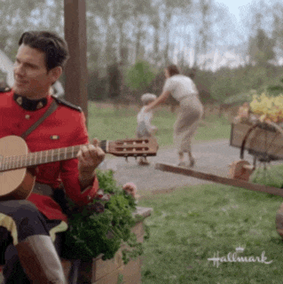 a man in a military uniform is playing a guitar in front of a woman and child