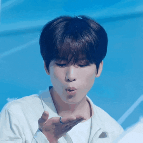 a young man blowing a kiss with a blue background