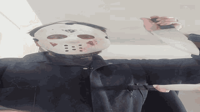 a man in a jason voorhees mask is holding a knife