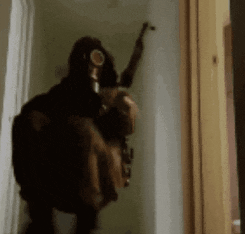 a person wearing a gas mask is holding a gun .