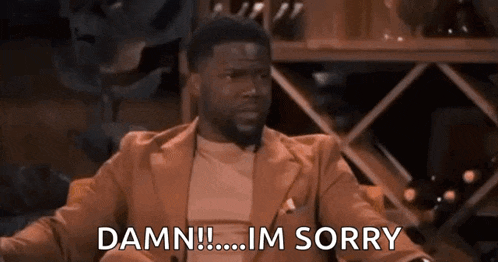 a man in a suit and tie is sitting in a chair and saying `` damn ! ... im sorry '' .