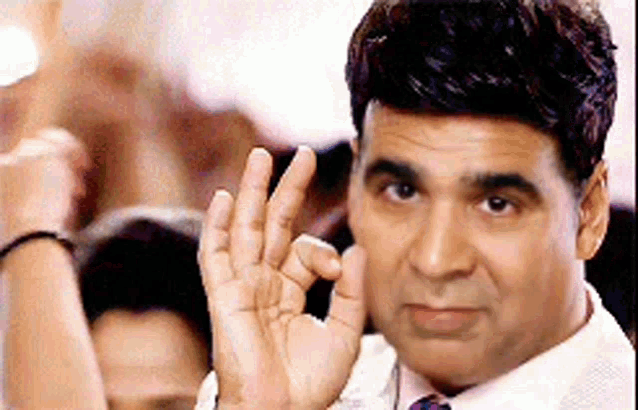 a man in a white shirt and tie is giving a ok sign