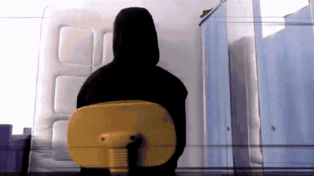 a person wearing a black hoodie sits in a yellow chair