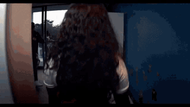 a man and a woman are standing in a room with a man in a black mask behind them