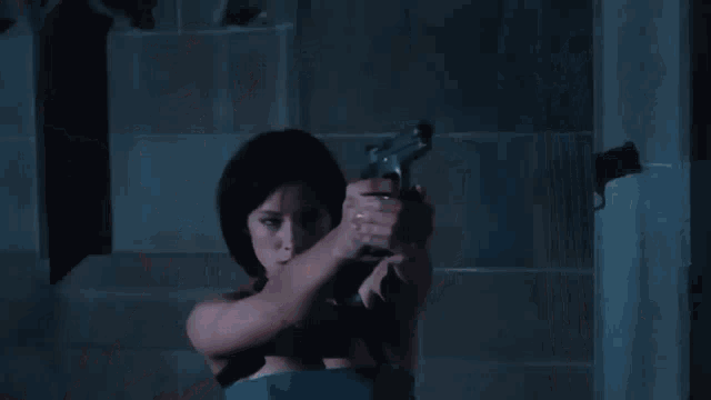 a woman in a blue dress is holding a gun in her hand and shooting it .