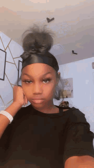 a woman wearing a headband is taking a selfie in a room .