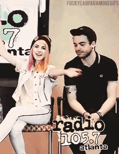 a man and a woman are sitting in front of a sign that says radio 105.7