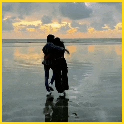 a man and a woman are hugging on a beach at sunset
