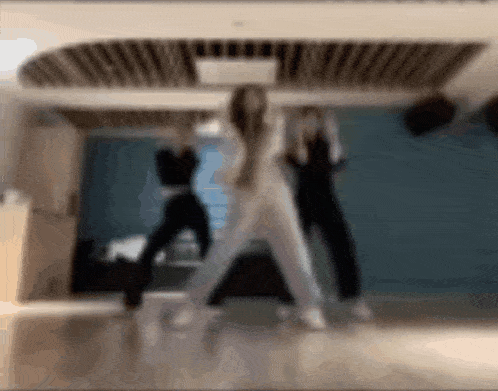 two women are dancing in a room with a blue wall .