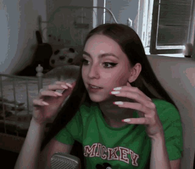 a woman wearing a green mickey t-shirt sits in front of a microphone