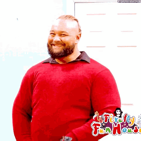a man with a beard is wearing a red sweater and laughing