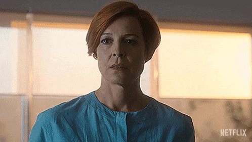 a woman in a blue shirt is standing in front of a window with netflix written on the bottom