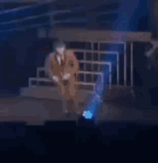 a man is dancing on a stage in front of a crowd in a dark room with blue lights coming out of the ceiling .