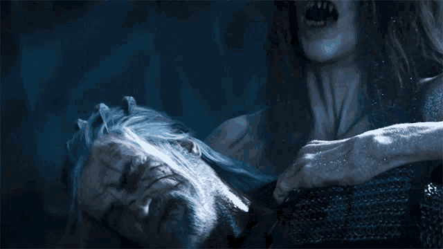 a man with a beard is being held by a woman with fangs