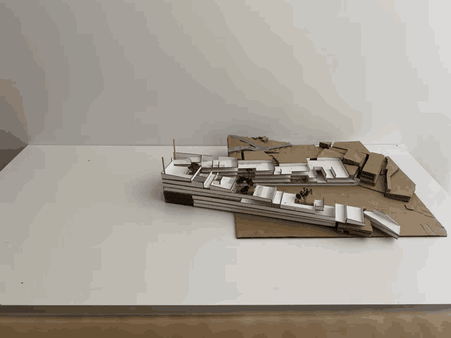 a cardboard model of a building sits on a white surface