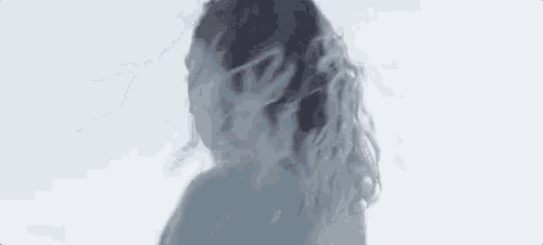a woman with long hair is standing in front of a white background with smoke coming out of her hair .
