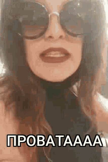 a woman wearing sunglasses and a black turtleneck is talking .