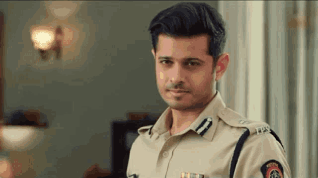 a man in a police uniform is standing in a living room .