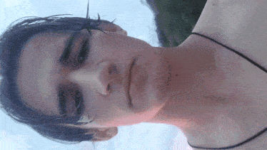 a man with a black necklace around his neck looks at the camera