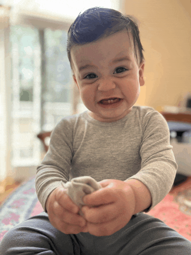 a baby is sitting on a bed and smiling
