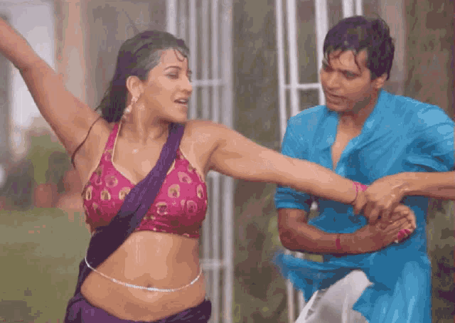 a woman in a purple top is dancing in the rain with a man in a blue shirt
