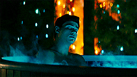 a man is taking a bath in a hot tub with a christmas tree in the background .
