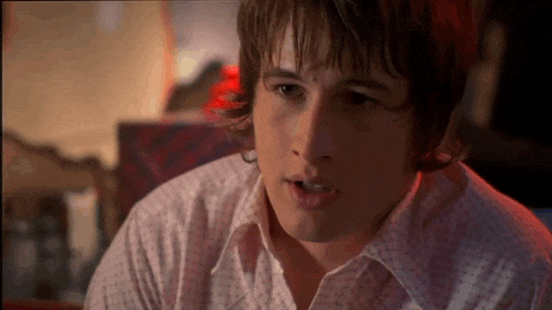 a close up of a young man 's face with a white shirt on