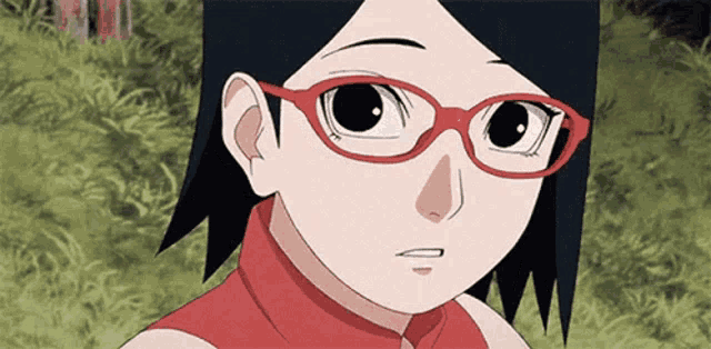 a close up of a girl wearing red glasses and a red shirt .