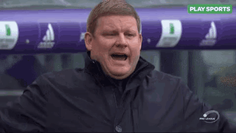 a man in a black jacket is screaming in front of a sign that says play sports