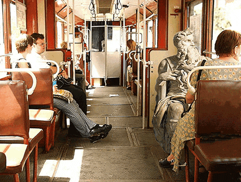 a statue of a man with a beard is sitting in the back of a bus