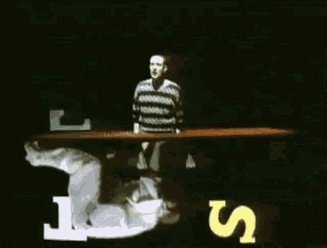 a man in a sweater stands in front of a love sign