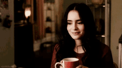 a woman in a red sweater is holding a red coffee mug