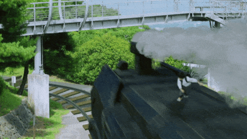 a train with smoke coming out of the chimney is going under a bridge