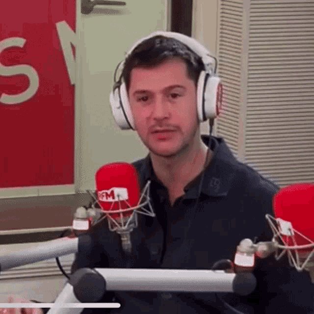 a man wearing headphones is sitting in front of a microphone in a radio station .