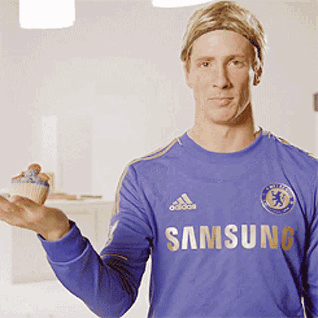 a man in a blue samsung shirt holds a cupcake